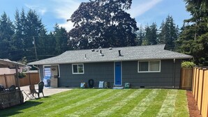 A residential property with a well-maintained lawn, a wooden fence, and a house with a blue door. - Awesome Little House ! (Mountlake Terrace)