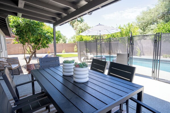 An outdoor patio with a table, chairs, and a pool.