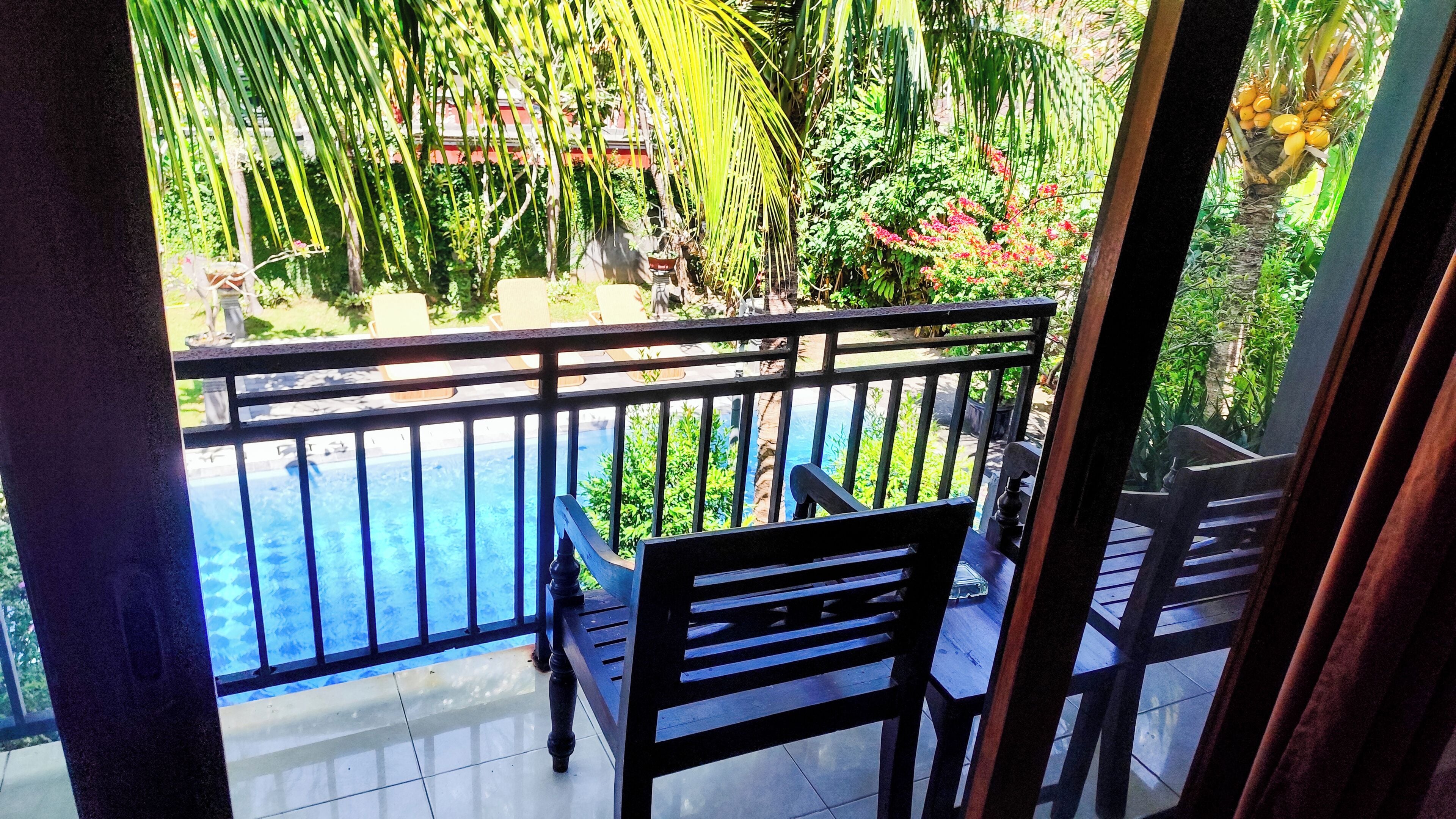 A balcony with a view of a swimming pool and lush greenery.