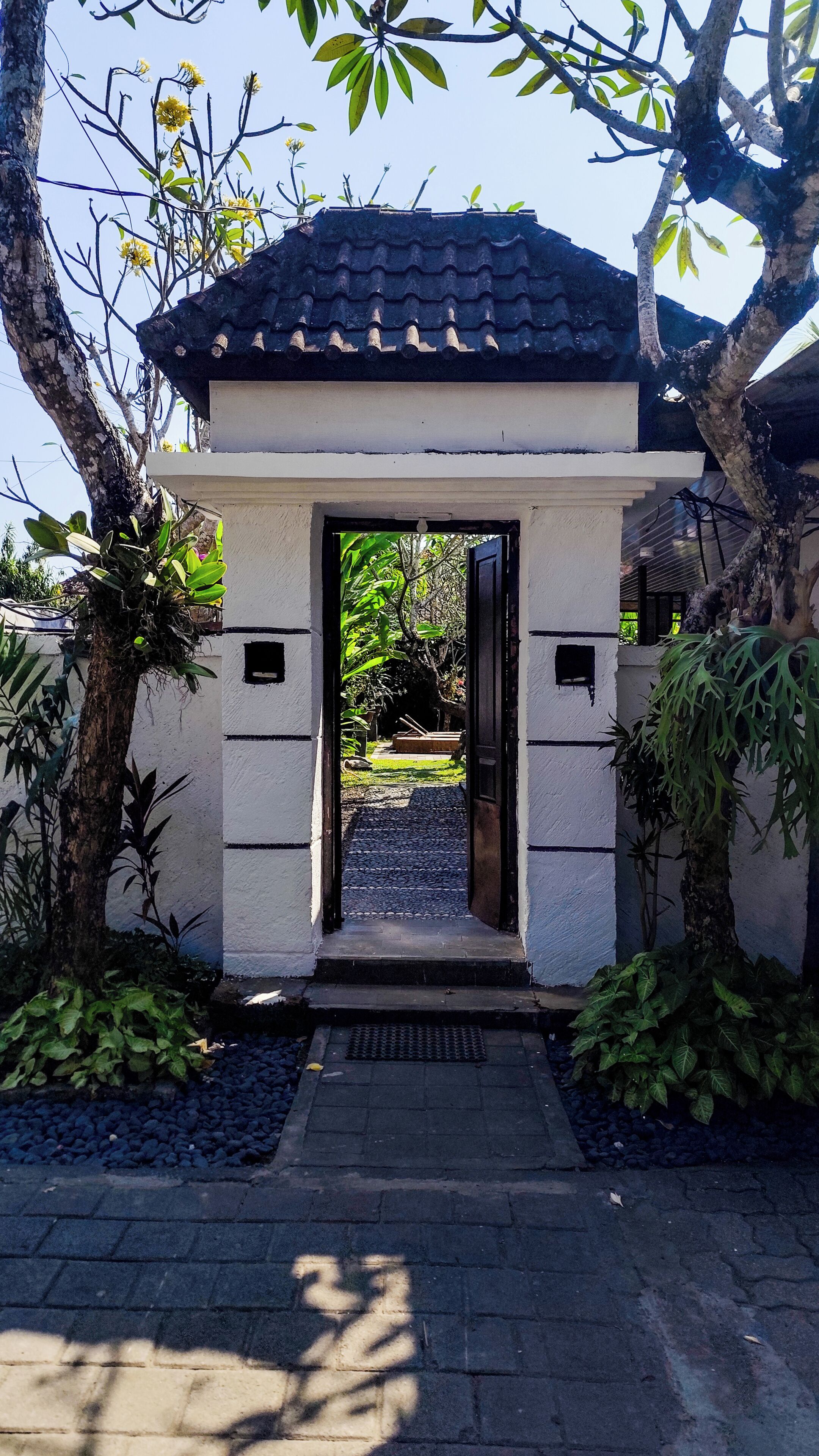 A traditional gate with a tiled roof, leading to a pathway.