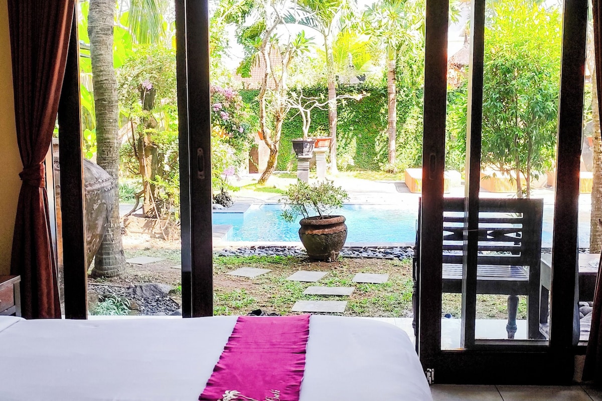 Une chambre d’hôtel avec un lit, une vue sur une piscine et un espace patio.