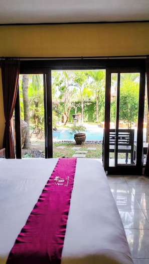 Une chambre d’hôtel avec un lit, une vue sur une piscine et un espace patio.