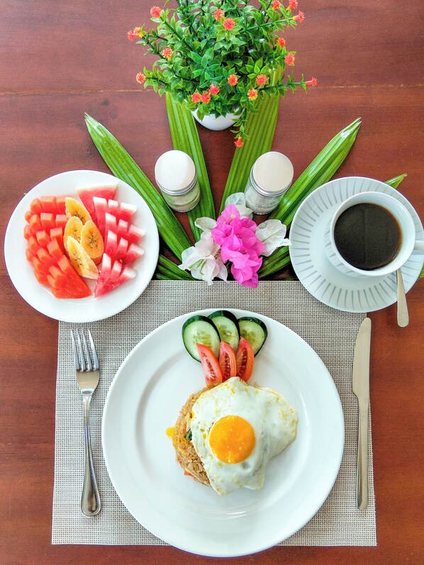 A table with a plate of food, a cup of coffee, and a flower arrangement.