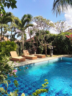 A swimming pool with lounge chairs and tropical plants. - Oemah Bali Nusa Dua (Nusa Dua)