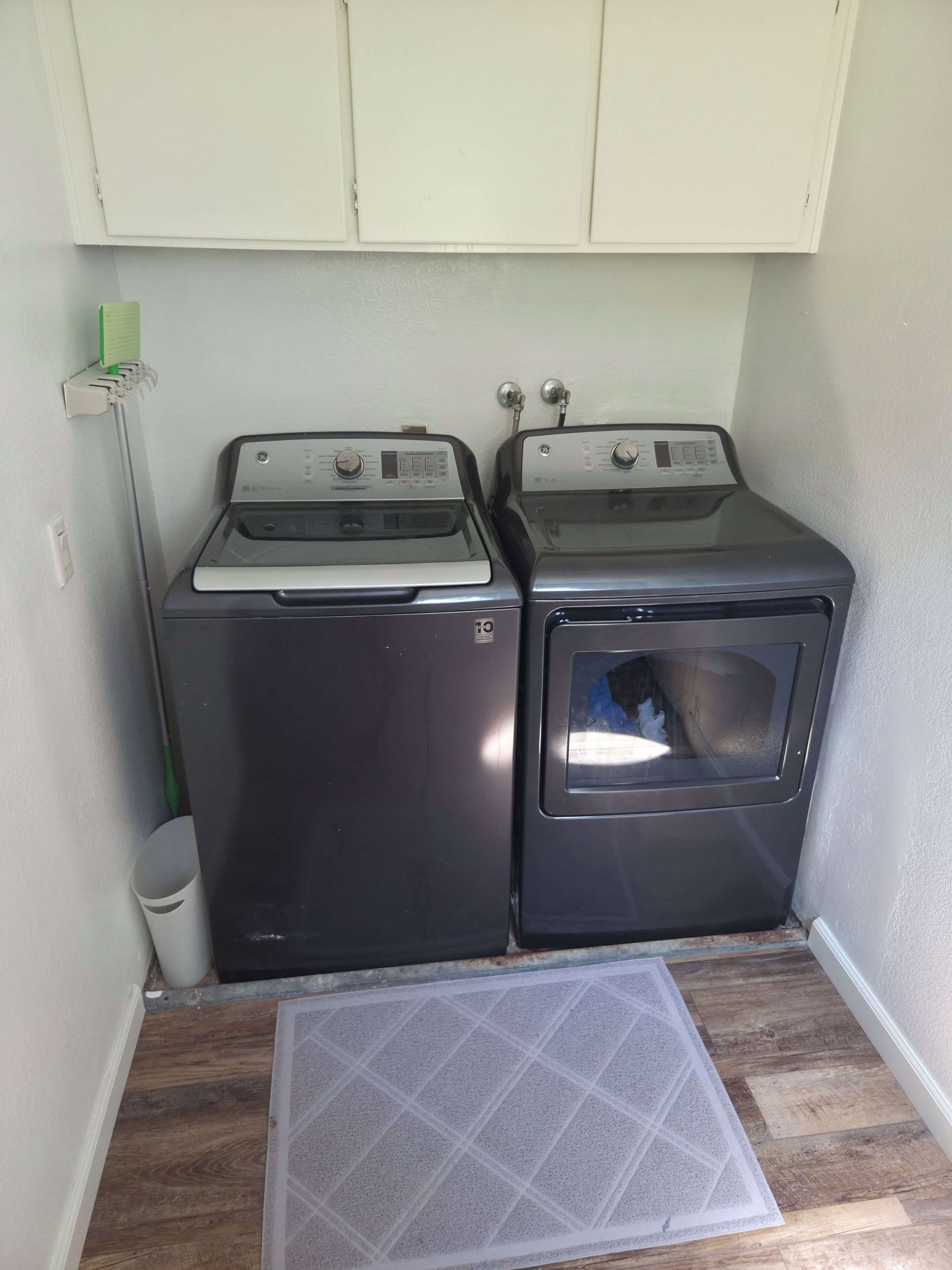 A laundry room with two stacked washing machines and a drying rack.