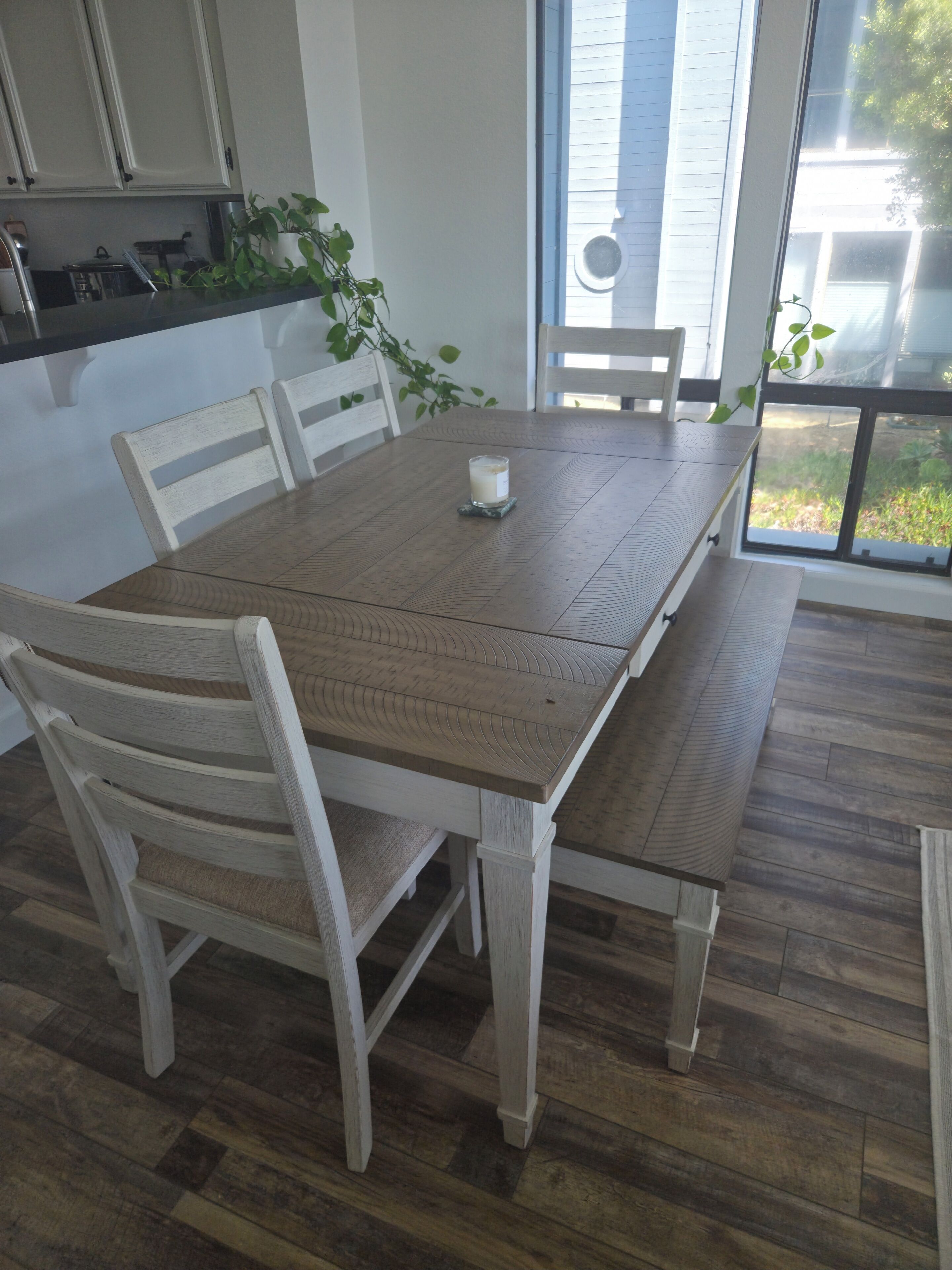 A dining table with chairs, a candle, and a potted plant.