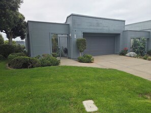 Una casa moderna de dos pisos amb garatge, gespa ben cuidada i diversos arbustos.