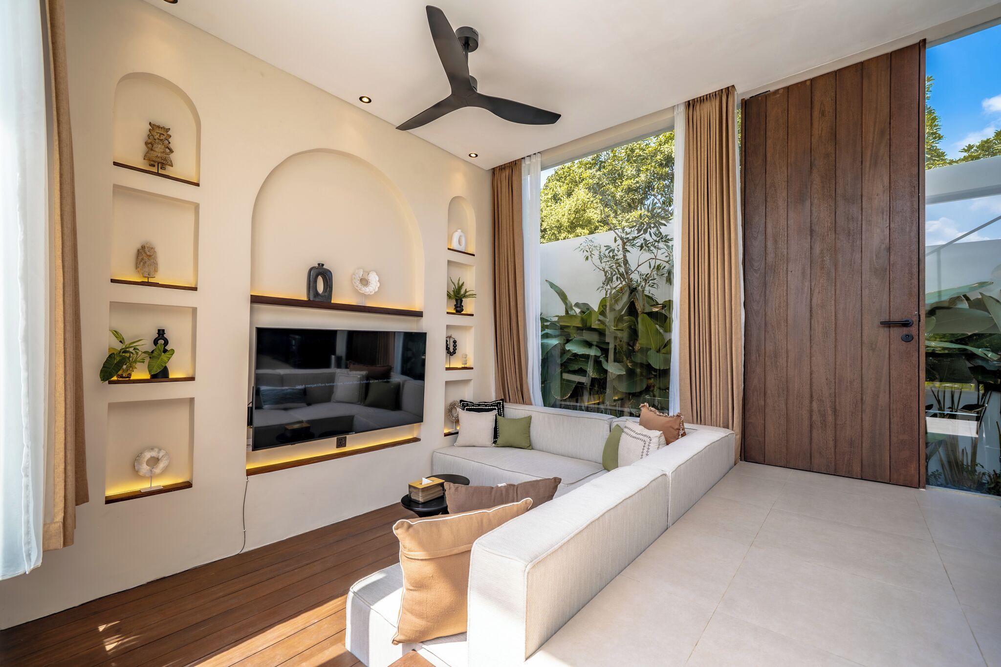 A modern living room with a sofa, TV, and decorative shelves.