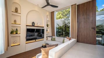 A modern living room with a sofa, TV, and decorative shelves.