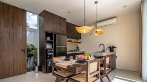Una cocina moderna con comedor, que incluye horno empotrado, pileta y una mesa de comedor con platos, vasos y una frutera.