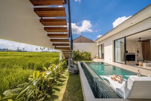 A modern house with a swimming pool, a wooden staircase, and a view of a green field. - Villa Ambisi Kedungu (Tabanan)