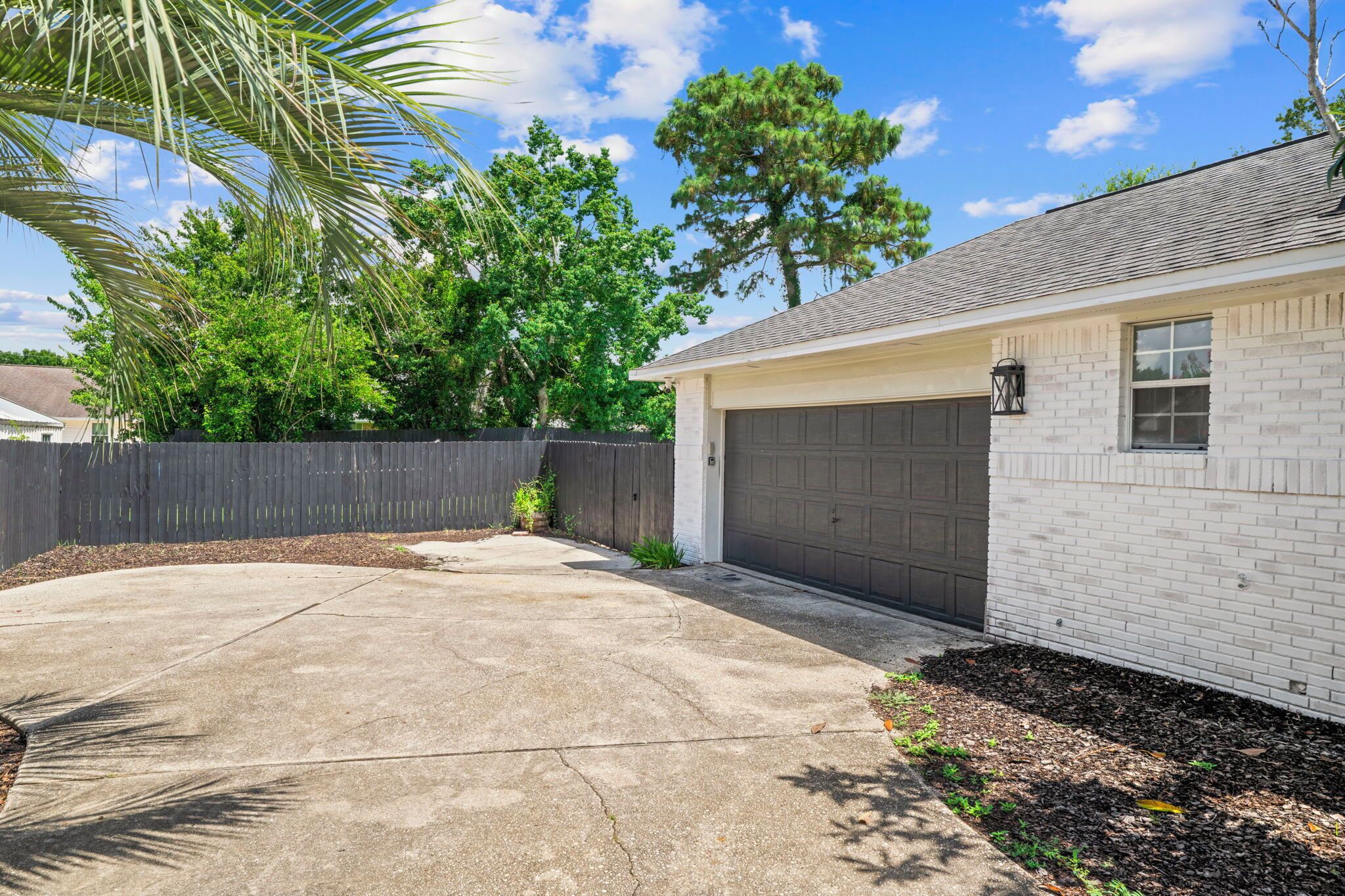 A residential garage with a white brick exterior and a dark garage door.