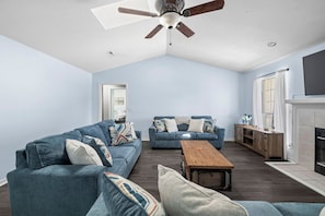 A living room with a ceiling fan, two sofas, a coffee table, and a fireplace.