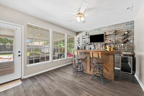 A bar area with a wooden counter, two stools, and a ceiling fan. - Tee & Sea | Pool, Golf & 8 Mi to Navarre Beach (Navarre)