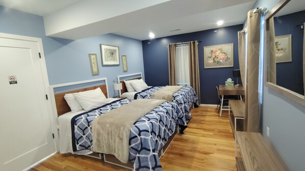 A hotel room with two beds, a desk, and a chair.