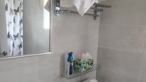 A bathroom with a white sink, a toilet, and a glass shelf with toiletries.