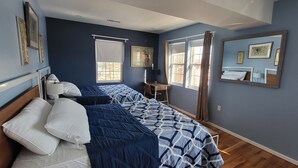 A bedroom with a bed, bedside tables, a desk, and a window with curtains.