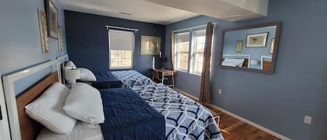 A bedroom with a bed, bedside tables, a desk, and a window with curtains.