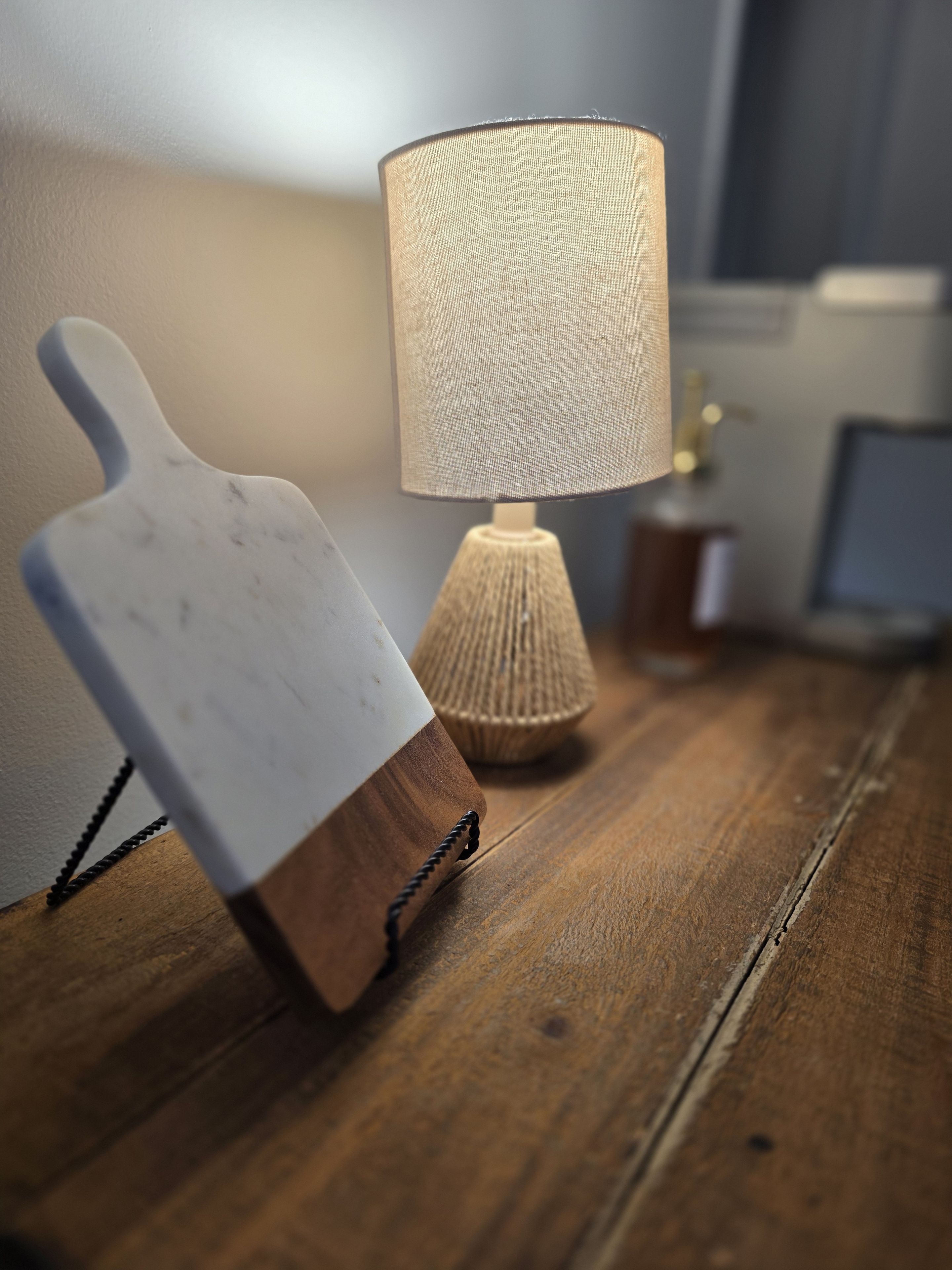 Ein Holztisch mit einer weißen Schneidebrett und einer Lampe mit einer strukturierten Lampenschirm.