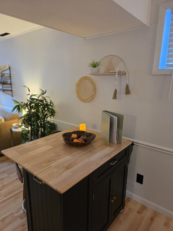 A kitchen island with a wooden countertop, a bowl of decorative pumpkins, and a potted plant.