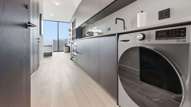 Una cocina moderna con lavadora y secadora integradas, un ventanal grande y un diseño minimalista.