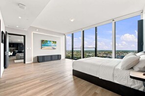 Ein modernes Schlafzimmer mit einem großen Bett, Blick auf die Stadt und einem Bild an der Wand.