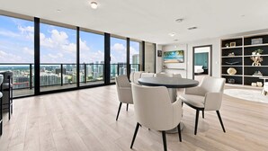 A spacious room with a large window, a round table, and modern furnishings. - 44th Floor at E11EVEN with Panoramic City Views (Miami)