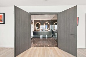 Un baño moderno con tocador, espejos y suelo de mármol.