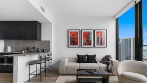 A modern living room with a sofa, a coffee table, and a city view through large windows. - 32nd Floor E11EVEN w/ Rooftop Pool & Skyline Views (Miami)