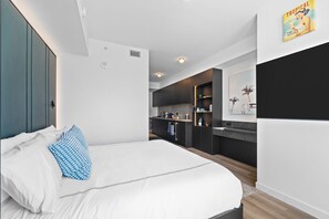 Ein modernes Schlafzimmer mit einem großen Bett, einer kleinen Küchenzeile und einem Badezimmer.