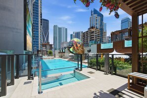 A rooftop pool with a glass barrier, surrounded by high-rise buildings and a colorful sculpture. - 15th Floor E11EVEN Retreat Near Miami Worldcenter (Miami)
