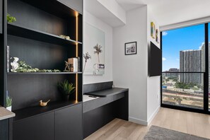 Ein modernes Interieur mit einer eingebauten Bücherwand, einer Küchenarbeitsplatte und einem großen Fenster mit Blick auf die Stadt.