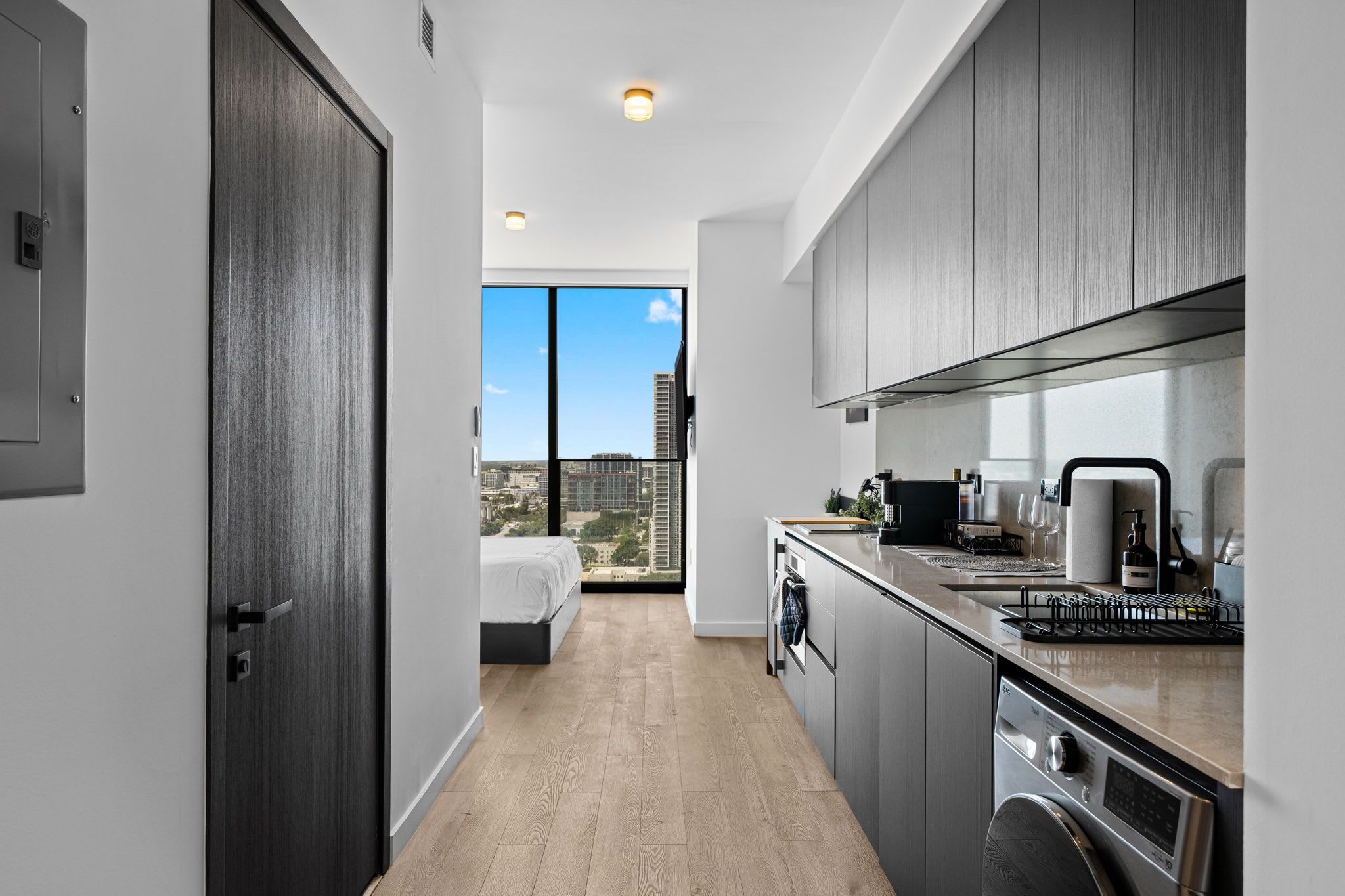 Une cuisine moderne avec vue sur la ville, un lit dans la pièce adjacente et une grande fenêtre.