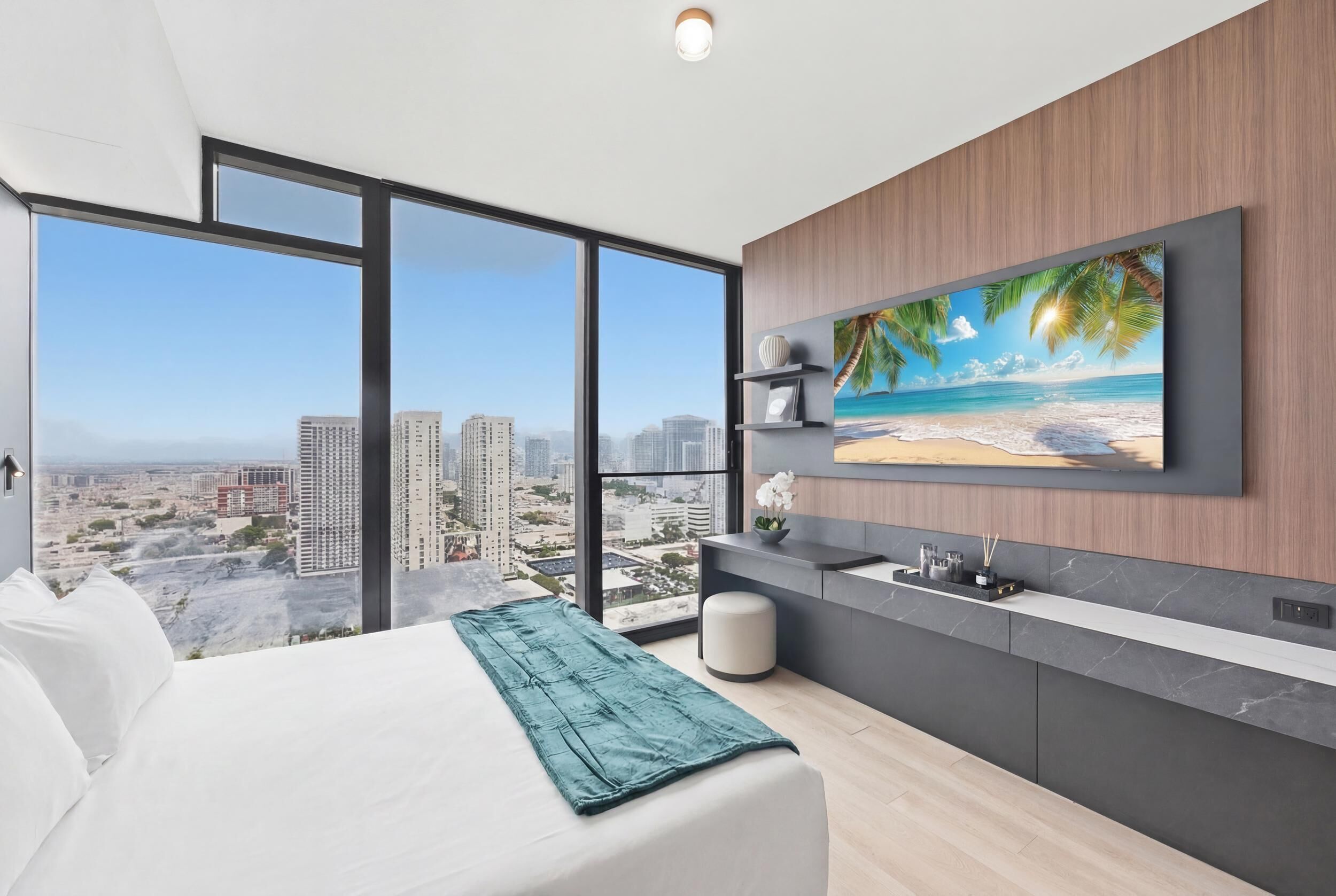 Une chambre d’hôtel moderne dotée d’un grand lit, offrant une vue sur la ville, comprenant un coin cuisine et une télévision diffusant des images de plage.