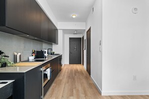 A modern kitchen with dark cabinetry, a wooden countertop, and a central island. - E11EVEN Studio Suite with Rooftop Pool & City Views (Miami)