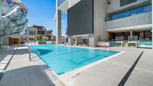 A modern hotel with a large indoor swimming pool, a unique hand sculpture, and a spacious balcony area. - Luxury 26th Floor Studio E11EVEN w/ Rooftop Pool (Miami)