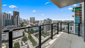 Un balcón con vista a la ciudad, que incluye edificios altos y una obra en construcción.