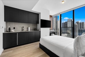 Une chambre d’hôtel moderne dotée d’un grand lit, d’une kitchenette et offrant une vue sur la ville.
