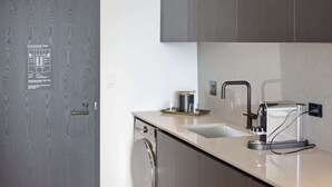 Una cucina moderna con lavello in acciaio inossidabile, macchina da caffè e pensile sopra il piano di lavoro.