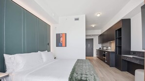 Una camera da letto moderna con un letto grande, una panca e un angolo cottura sullo sfondo.