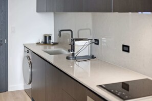 Eine moderne Küche mit eingebautem Geschirrspüler, einer Edelstahl-Spüle und einer eleganten Arbeitsplatte.