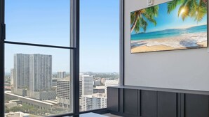 Una habitación con un ventanal grande con vistas a un paisaje urbano, un cuadro de una escena de playa y una decoración interior moderna.