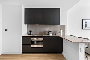 A modern kitchen with dark cabinetry, stainless steel appliances, and a light-colored countertop. - E11EVEN 25th Floor Residence w/ Skyline Views (Miami)