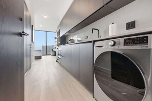 A modern kitchen with a built-in washer and dryer, a large window, and a minimalist design. - 40th Floor E11EVEN Studio w/ Skyline Views (Miami)