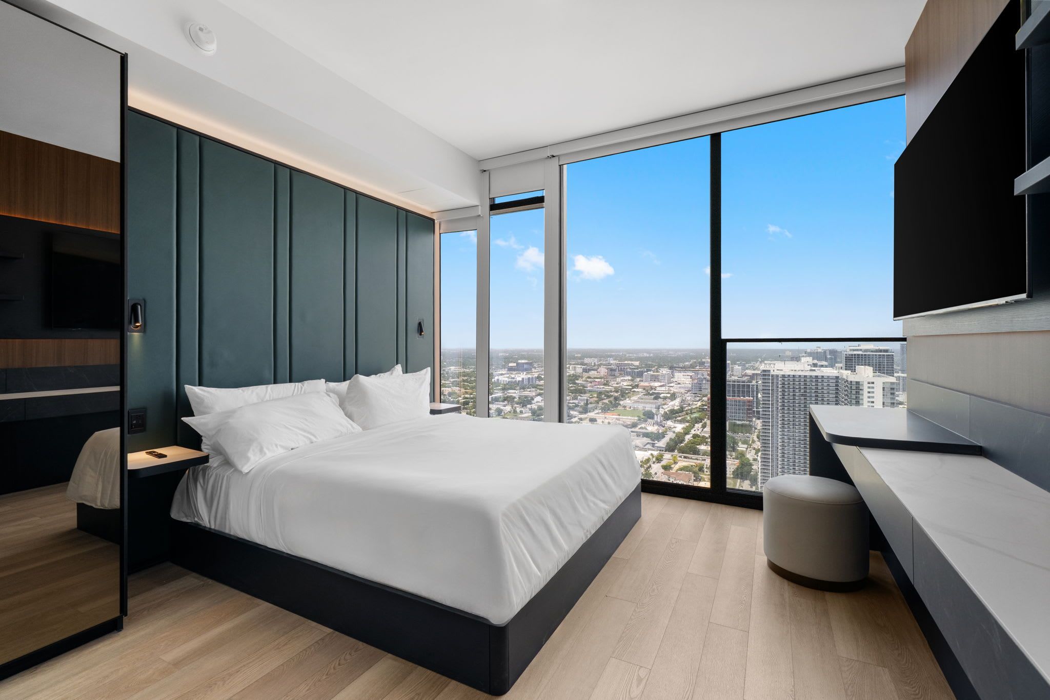 Un dormitorio moderno con una cama grande, un escritorio y vistas a la ciudad.