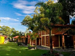 Un patio con un edificio de ladrillo, una palmera y un pequeño jardín.