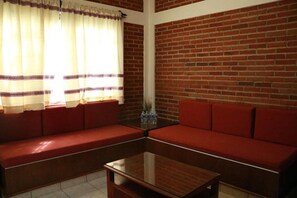 A room with a red sofa, a glass coffee table, and a brick wall. - Cabañas del Bosque (San Miguel Regla)