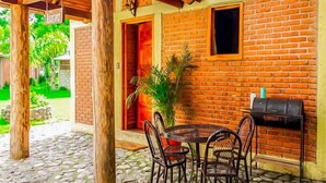 An outdoor patio with a brick wall, a round table with chairs, and a grill.