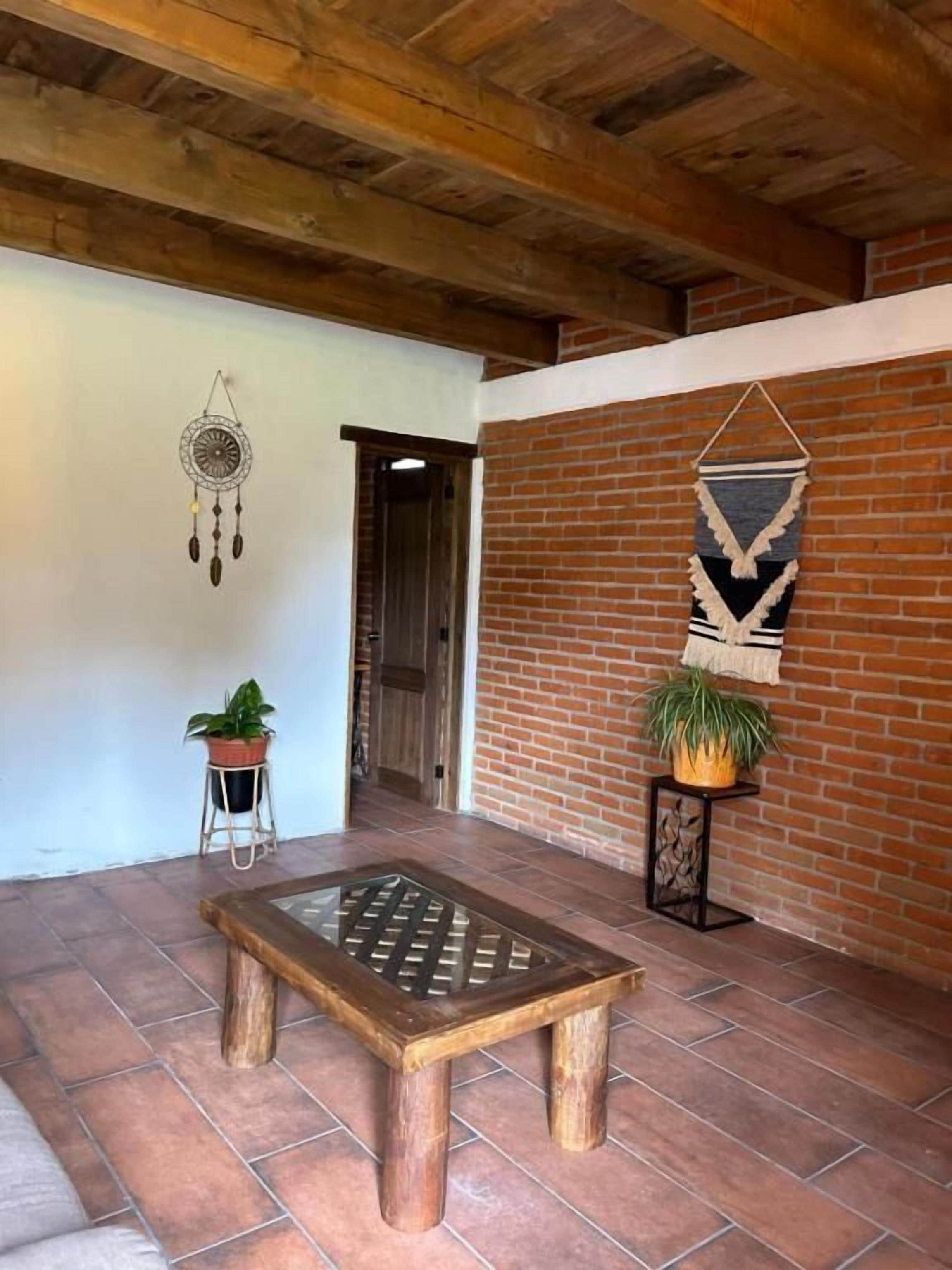 Un banco de madera en una habitación con pared de ladrillo y techo a la vista.