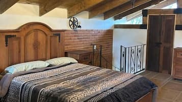 Un dormitorio con techo de madera, una cama con ropa de cama estampada, una mesita de noche y un reloj de pared.